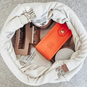 Open makeup bag with cosmetic items including an orange jewellery box