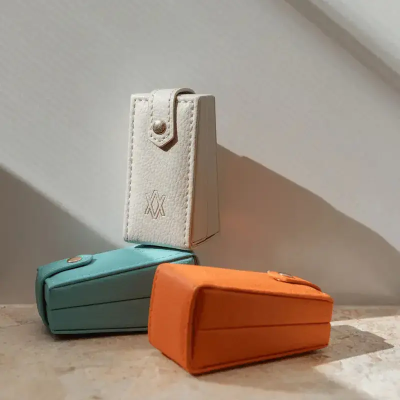 Three small jewellery boxes in stone turquoise, and orange on a light surface.